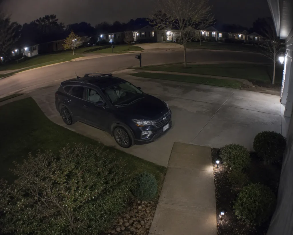 Outdoor security camera color night vision footage of a driveway and front walkway